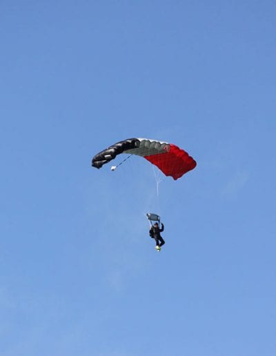 Man descending in a red white and blue nine cell Falcon parachute