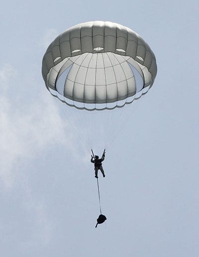 Man descending in an Invasion II parachute with separated bag