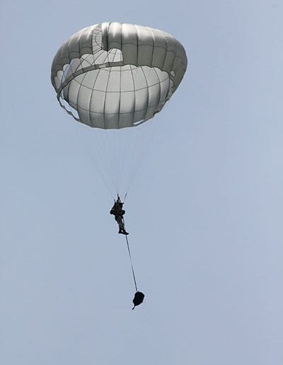 Man descending in an Invasion II parachute with separated bag